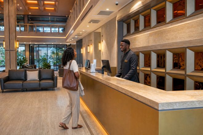 A concierge greeting a resident at the reception desk of a residential building